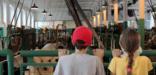 Boott Mills weave room with two children watching the looms from behind a railing